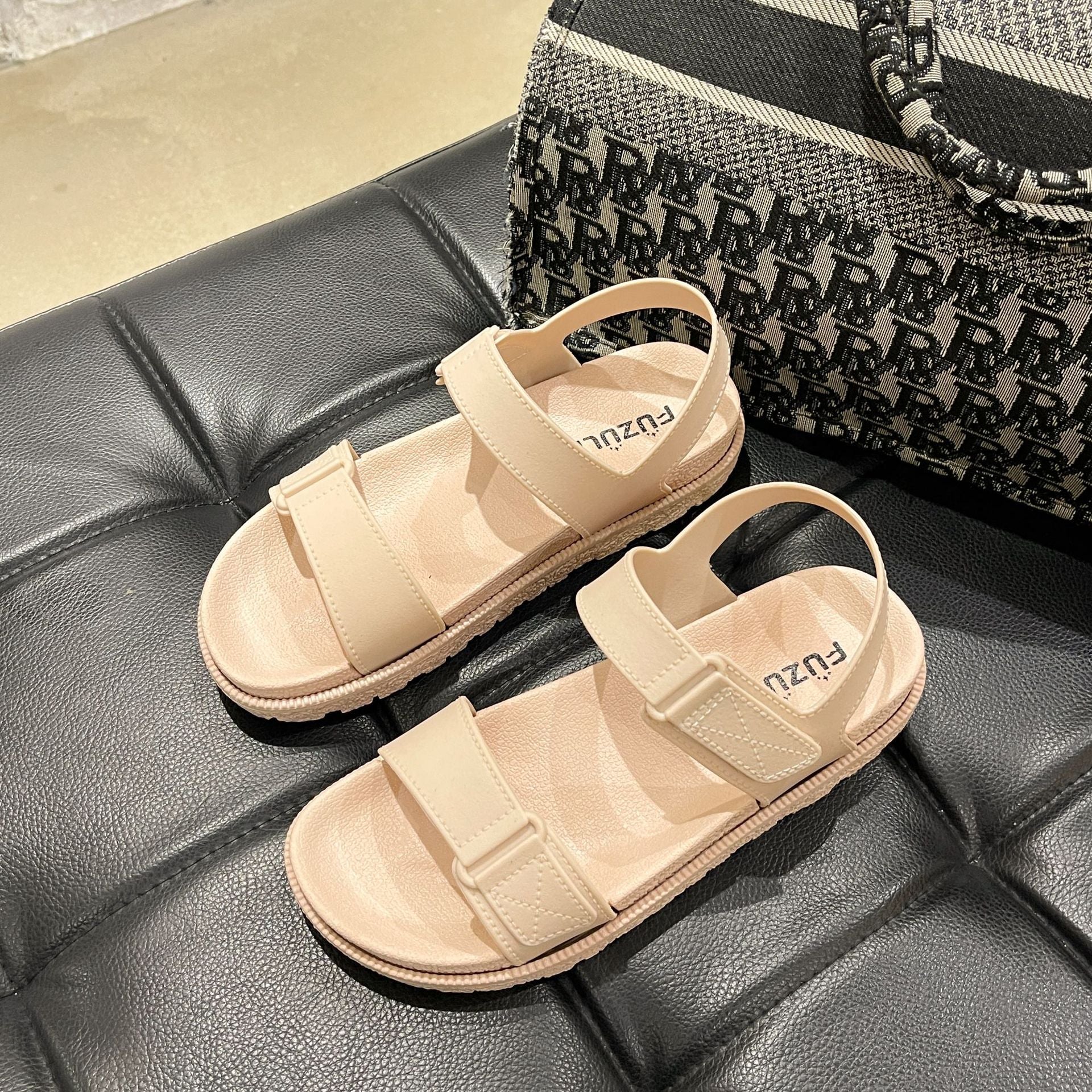 Beige flade sandaler med velcro og tyk sål set oppefra på sort lædersæde — Venzelo