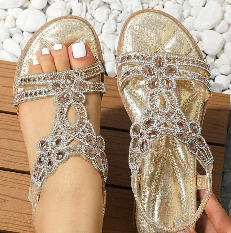 Guld sandal med rhinsten blomsterrem og åben tå set oppefra på to fødder — Venzelo