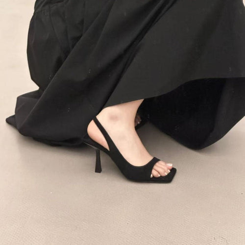 Sort slingback sandal med firkantet tå og skulptureret stilethæl set fra siden under sort kjole — Venzelo