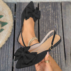 Sort slingback fladsko med sløjfe holdt i hånden, detalje på spænde og foer synlig — Venzelo