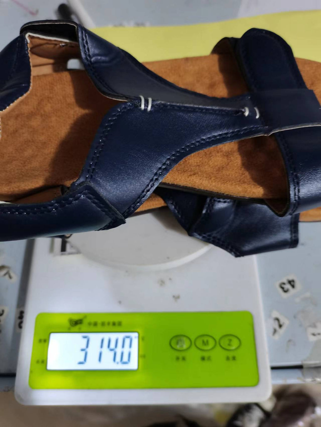 Marineblå sandal liggende på vægt, nærbillede der viser sål og velcro-detalje — Venzelo