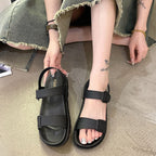 Sort sandal holdt i hånden ved siden af fod iført sort sandal med tyk sål — Venzelo